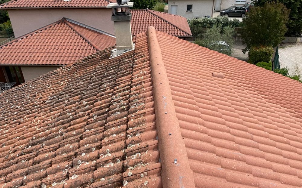 Toiture en tuiles béton dont un versant est encore couvert de lichens et l'autre après démoussage complet
